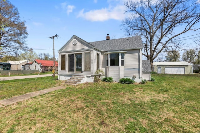view of front of property with a chimney, a shingled roof, a front lawn, and an outdoor structure