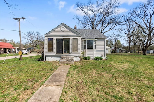 view of front of house with a front yard, a chimney, and roof with shingles