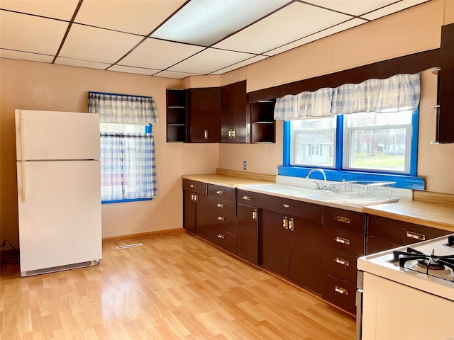 kitchen featuring freestanding refrigerator, light wood-type flooring, light countertops, and a paneled ceiling