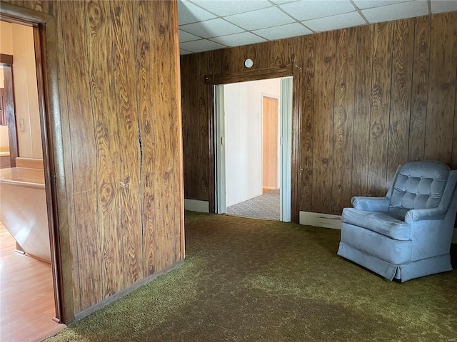 sitting room with wood walls, carpet flooring, and a paneled ceiling