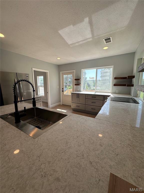 403 Broadway St, Waynesville, MO 65583 - kitchen featuring a sink, open shelves, a textured ceiling, gray cabinetry, and light stone countertops