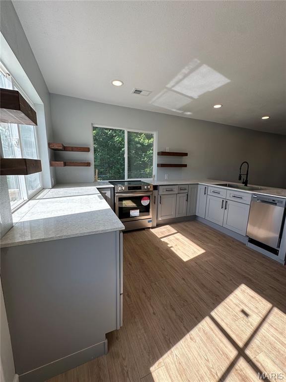 403 Broadway St, Waynesville, MO 65583 - kitchen with appliances with stainless steel finishes, open shelves, gray cabinets, a sink, and wood finished floors
