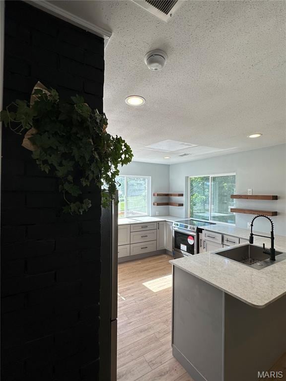403 Broadway St, Waynesville, MO 65583 - kitchen with a sink, stainless steel range with electric cooktop, a textured ceiling, a peninsula, and light wood finished floors