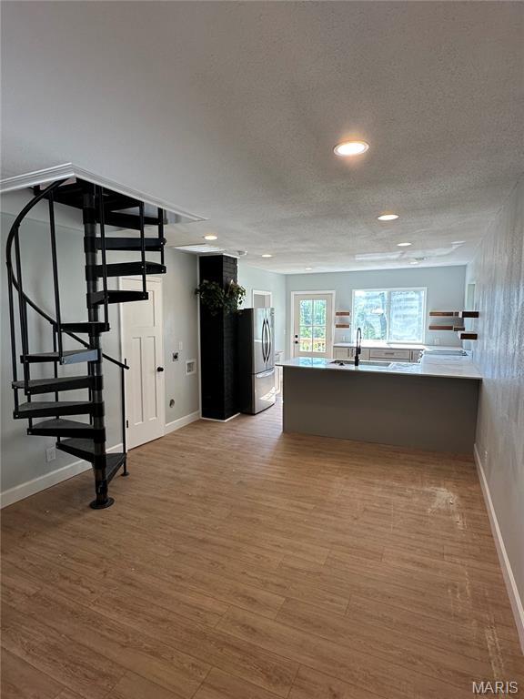 403 Broadway St, Waynesville, MO 65583 - kitchen with freestanding refrigerator, wood finished floors, a textured ceiling, baseboards, and a peninsula