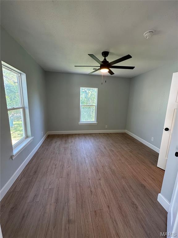 403 Broadway St, Waynesville, MO 65583 - empty room with plenty of natural light, dark wood finished floors, and baseboards