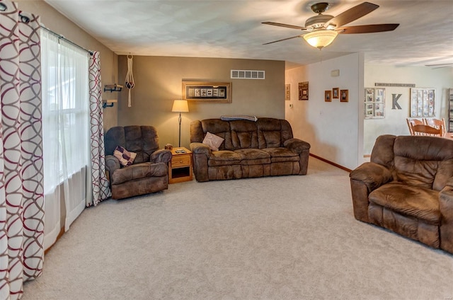living area with ceiling fan, carpet, and baseboards