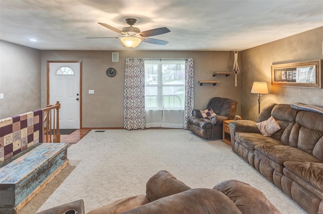 carpeted living area with ceiling fan and baseboards