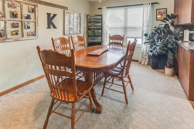 dining space featuring light colored carpet and baseboards