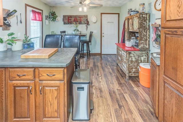 kitchen with brown cabinetry, dark wood-style floors, and ceiling fan