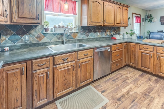 kitchen featuring stainless steel dishwasher, a sink, brown cabinets, and decorative backsplash
