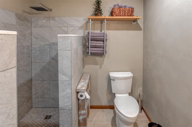 bathroom with tiled shower, toilet, and tile patterned floors