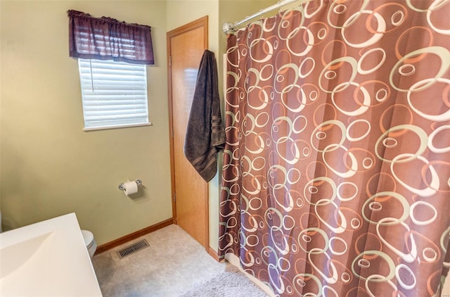 bathroom with a shower with curtain, toilet, and baseboards