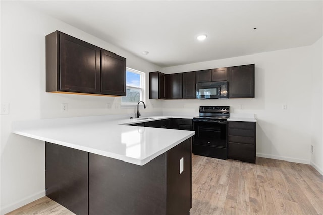 407 Fleming Cir, Wentzville, MO 63385 - kitchen with black appliances, a sink, a peninsula, dark brown cabinets, and light wood finished floors