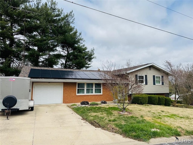 1423 Shelley Dr, Vandalia, IL 62471 - split level home featuring a garage, brick siding, concrete driveway, solar panels, and a front lawn