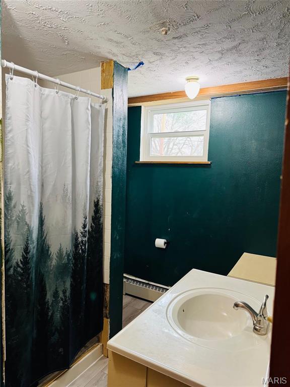 1423 Shelley Dr, Vandalia, IL 62471 - bathroom with a baseboard heating unit, a shower stall, a textured ceiling, and vanity