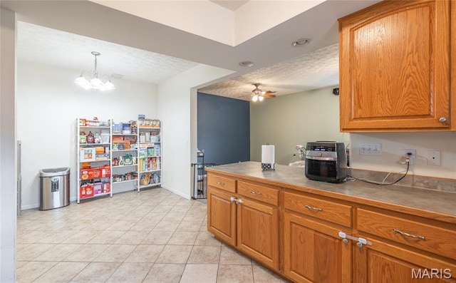 22354 Target Rd, Saint Robert, MO 65584 - kitchen featuring brown cabinets, a ceiling fan, light tile patterned floors, baseboards, and a textured ceiling