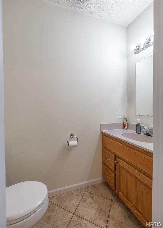 22354 Target Rd, Saint Robert, MO 65584 - bathroom featuring vanity, toilet, tile patterned flooring, baseboards, and a textured ceiling