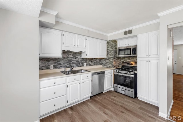 1220 Spring Valley Dr, Florissant, MO 63033 - kitchen with stainless steel appliances, a sink, white cabinets, tasteful backsplash, and crown molding