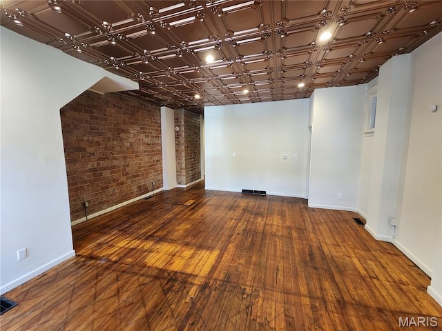 4713 Virginia Ave, Saint Louis, MO 63111 - spare room with brick wall, wood-type flooring, and baseboards
