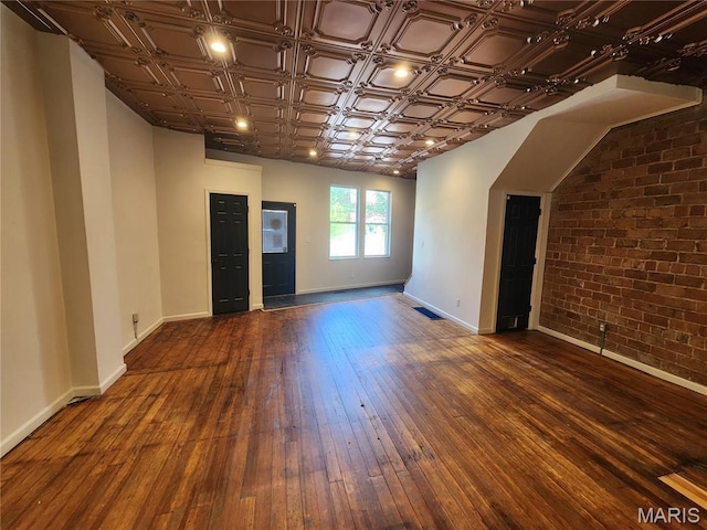 4713 Virginia Ave, Saint Louis, MO 63111 - empty room featuring brick wall, baseboards, dark wood finished floors, and an ornate ceiling