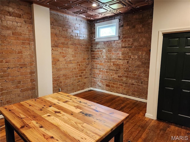 4713 Virginia Ave, Saint Louis, MO 63111 - below grade area with dark wood finished floors, brick wall, baseboards, and an ornate ceiling