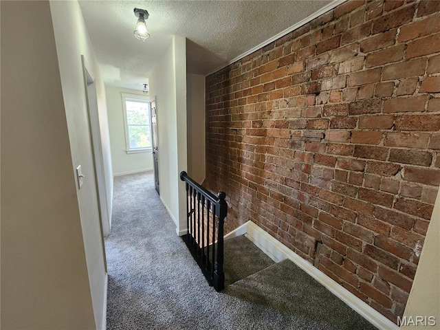 4713 Virginia Ave, Saint Louis, MO 63111 - hall with an upstairs landing, brick wall, a textured ceiling, carpet, and baseboards