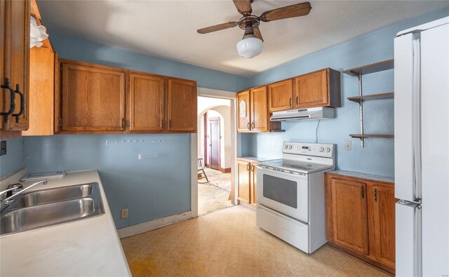104 E Jefferson Ave, Richland, MO 65556 - kitchen with white appliances, under cabinet range hood, a sink, brown cabinets, and arched walkways