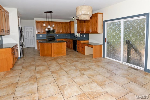 kitchen featuring stainless steel appliances, a center island, dark countertops, and brown cabinets