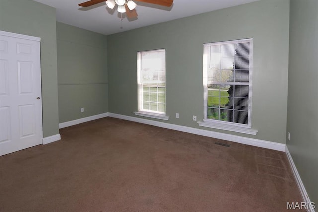 unfurnished room featuring dark carpet, a ceiling fan, and baseboards