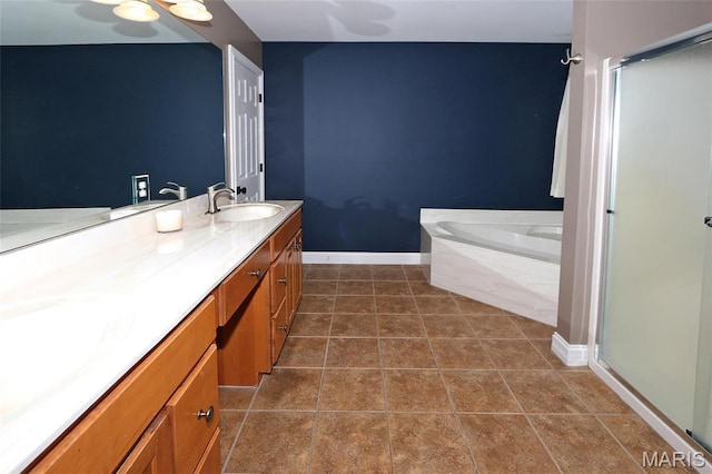bathroom with a stall shower, baseboards, vanity, and a garden tub