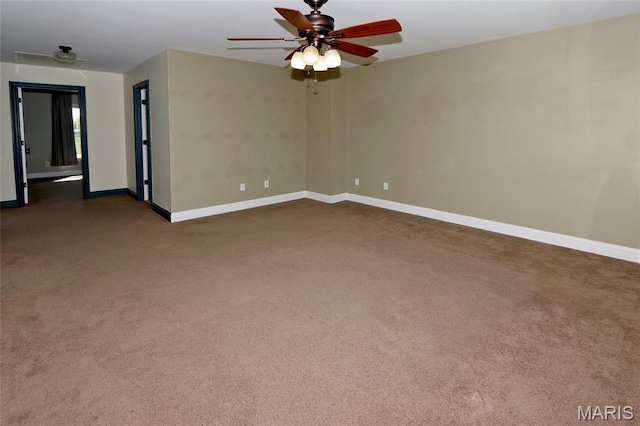 spare room featuring dark carpet, a ceiling fan, and baseboards