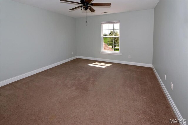 spare room featuring dark carpet, ceiling fan, and baseboards