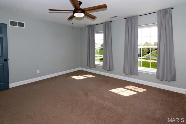 carpeted empty room featuring baseboards, ceiling fan, and plenty of natural light