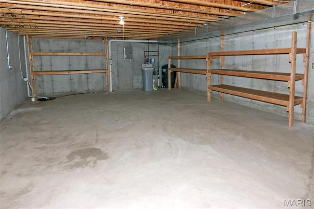 unfinished basement featuring electric panel and a water pressure tank