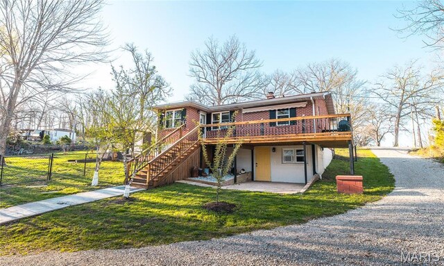 view of front of property featuring a wooden deck, brick siding, driveway, a chimney, and stairway
