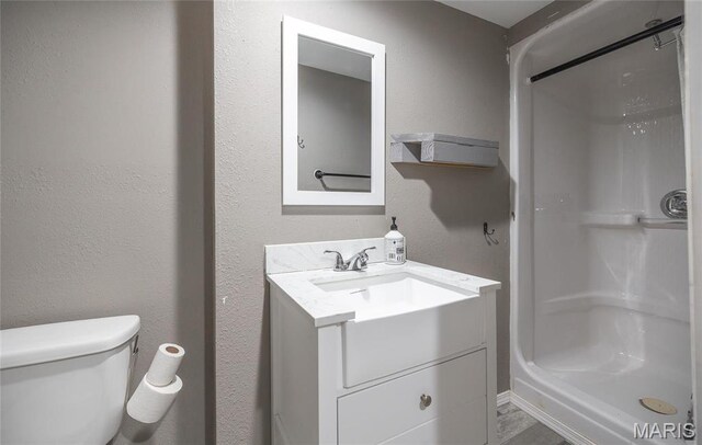 full bathroom featuring a stall shower, vanity, and toilet