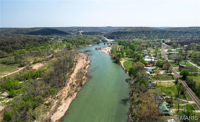 view of property location with a nearby body of water and a forest