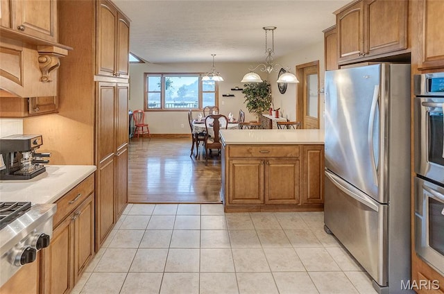3448 Levee Rd, Centralia, IL 62801 - kitchen featuring stainless steel appliances, brown cabinetry, light countertops, pendant lighting, and a peninsula