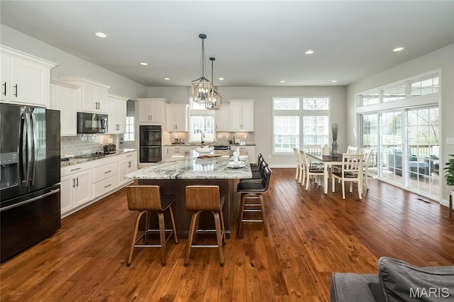 2181 Jarvis Rd, Foristell, MO 63348 - kitchen with black appliances, a kitchen bar, white cabinets, and recessed lighting