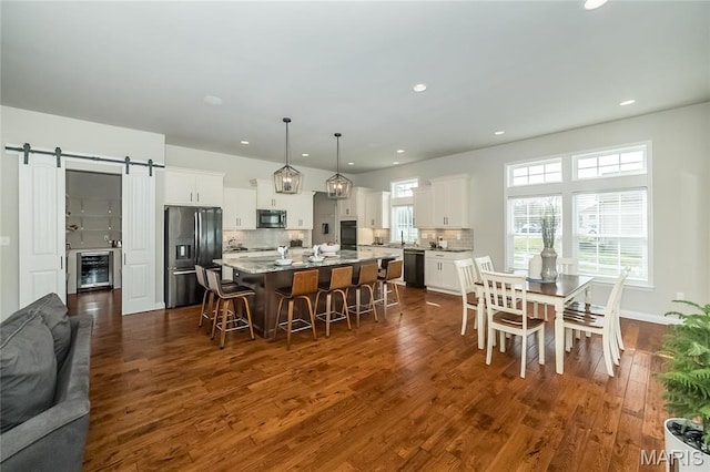 2181 Jarvis Rd, Foristell, MO 63348 - kitchen featuring black appliances, a barn door, a breakfast bar, a kitchen island, and dark wood-type flooring