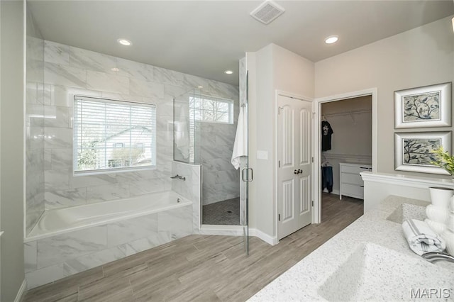 2181 Jarvis Rd, Foristell, MO 63348 - bathroom featuring a shower stall, a bath, wood finished floors, recessed lighting, and a walk in closet