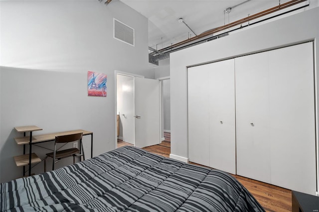 bedroom with wood finished floors, a high ceiling, and a closet