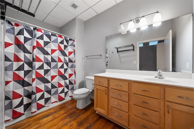 bathroom featuring wood finished floors, vanity, toilet, a shower with shower curtain, and a paneled ceiling