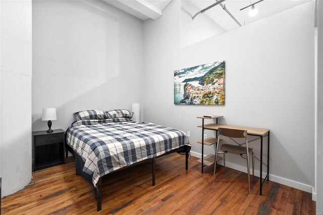 bedroom featuring hardwood / wood-style floors, baseboards, and track lighting