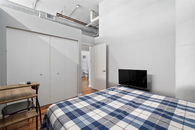 bedroom featuring a high ceiling, wood finished floors, and a closet