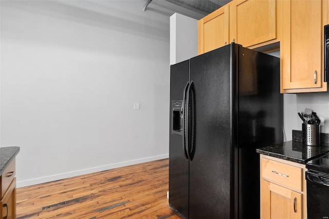 kitchen with black fridge with ice dispenser, wood finished floors, baseboards, dark stone countertops, and light brown cabinets