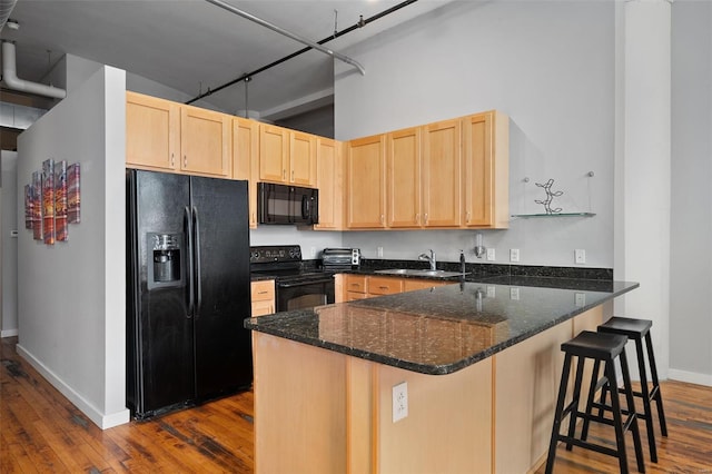 kitchen featuring black appliances, light brown cabinetry, a sink, baseboards, and a peninsula
