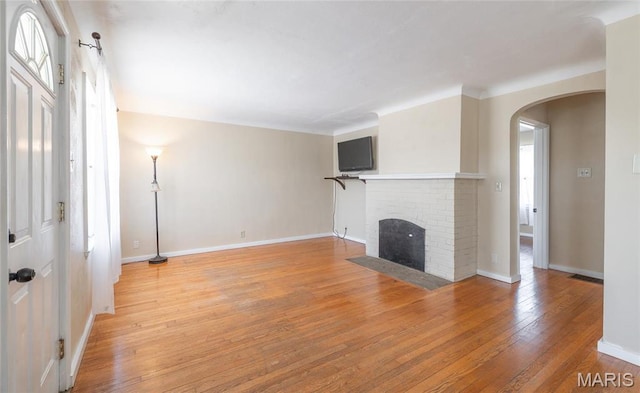 11 Rolla Gardens Dr, Rolla, MO 65401 - unfurnished living room with arched walkways, light wood-style floors, baseboards, and a brick fireplace