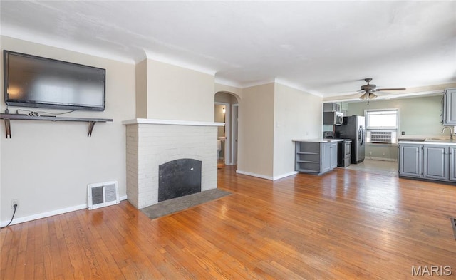 11 Rolla Gardens Dr, Rolla, MO 65401 - unfurnished living room featuring arched walkways, ceiling fan, a sink, and light wood-style flooring
