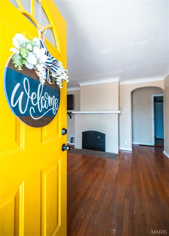 11 Rolla Gardens Dr, Rolla, MO 65401 - unfurnished living room featuring arched walkways, hardwood / wood-style floors, and a brick fireplace